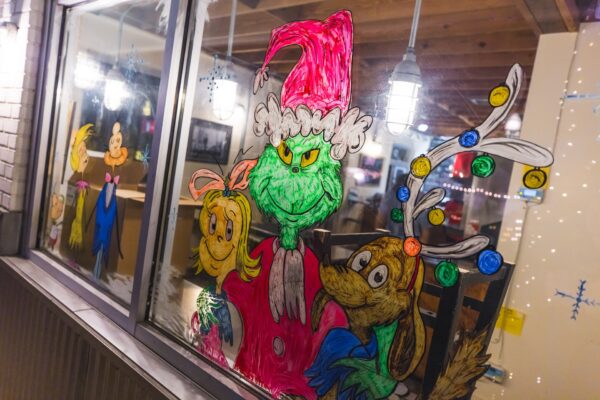 Hand-painted Grinch and Whoville characters decorate a window during Dickens on Centre on Amelia Island