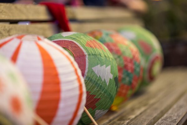 Colorful paper lanterns with holiday patterns on a wooden bench at Dickens on Centre Amelia Island