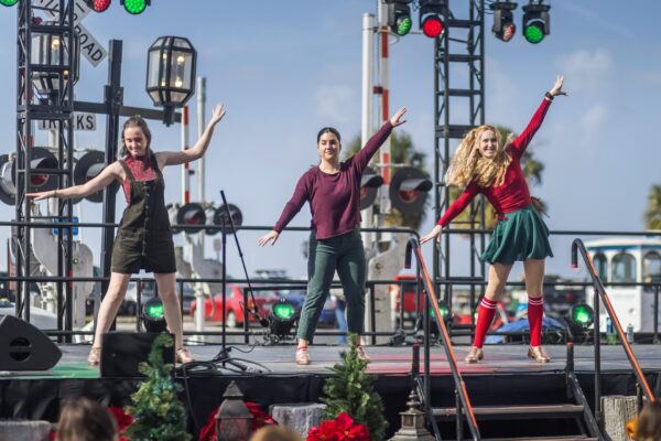 Three performers dance on an outdoor stage during the Dickens on Centre festival on Amelia Island