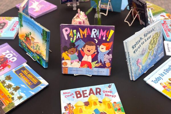 A colorful display of children’s books arranged on a round table, with the book Pajamarama! prominently featured in the center among other vibrant picture books.