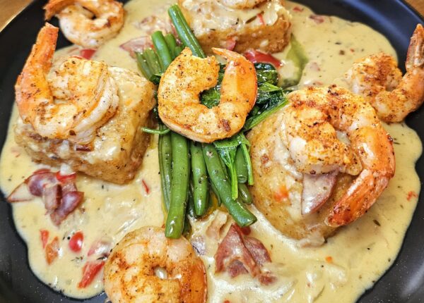 Shrimp and grit cakes served in a creamy sauce with green beans and bacon.