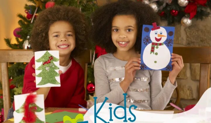 Two smiling children sit at a table holding up handmade holiday cards—a Christmas tree and a snowman—with craft supplies around them. A decorated Christmas tree and fireplace are in the background. Text reads, “Kids Gift-Making!”.