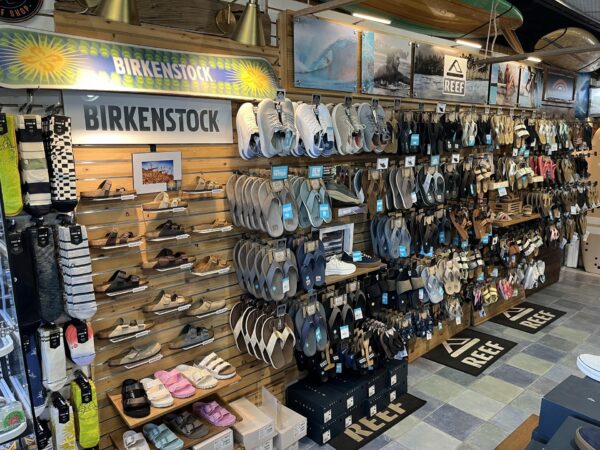 Retail store wall display featuring various Birkenstock and Reef sandals, socks, and branded signage.