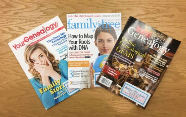 Three genealogy magazines—YouGenealogy!, Family Tree Magazine, and Family Tree—are spread out on a wooden surface. Each cover features headlines about family history research and DNA ancestry.