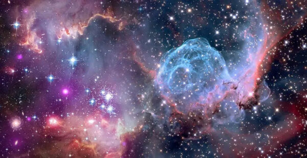 Colorful nebula and star field in deep space. Bright stars, glowing clouds of gas and dust, and various hues of blue, pink, and purple create a vibrant, cosmic scene.