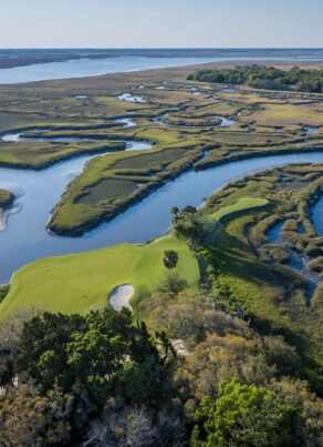 Aerial view of a golf green surrounded by salt marsh waterways.