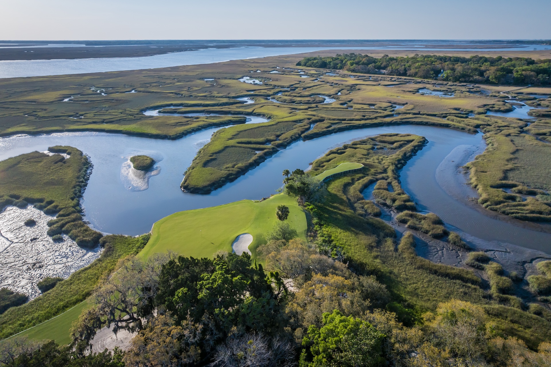 Aerial view of a golf green surrounded by salt marsh waterways.