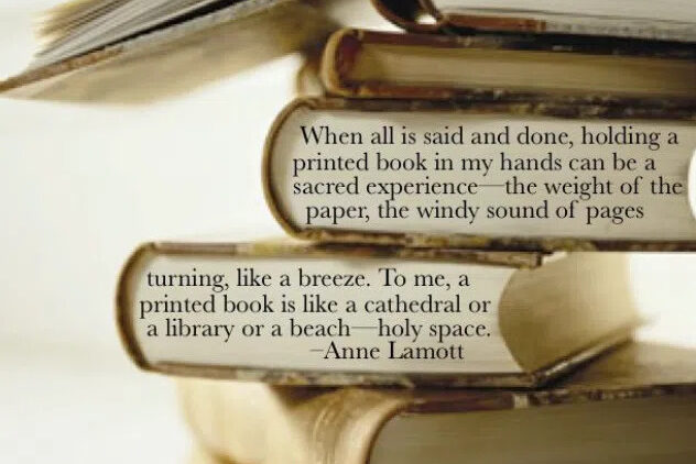 A close-up of a stack of books with an open book on top. Overlaid is an Anne Lamott quote about the sacred experience of holding a printed book, comparing it to a cathedral, library, or holy space.