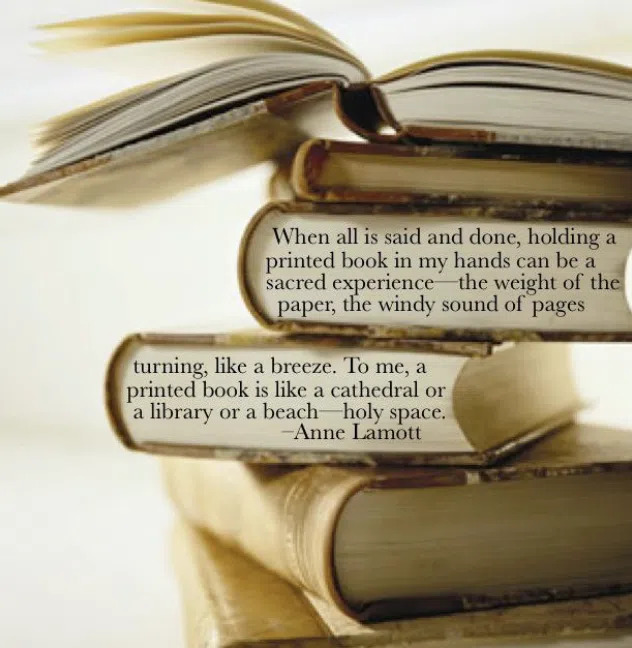 A close-up of a stack of books with an open book on top. Overlaid is an Anne Lamott quote about the sacred experience of holding a printed book, comparing it to a cathedral, library, or holy space.