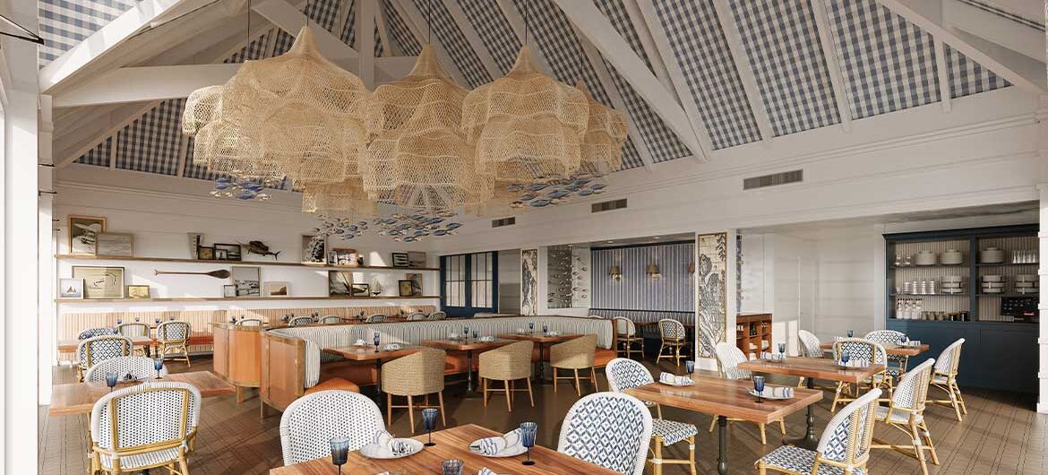 Coastal-style restaurant with high, beamed ceiling, wicker chandeliers, patterned blue and white chairs, wooden tables set with napkins and glasses, and a bright, airy ambiance.