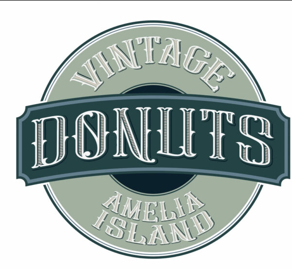 A circular logo with the text Vintage Donuts Amelia Island in bold, stylized lettering on a green and cream background.
