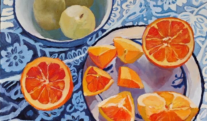A vibrant painting depicts pears in a bowl and sliced oranges on plates, resting on a blue patterned tablecloth with floral and leaf designs. The fruits vivid colors contrast with the cool blue background.