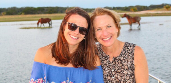 women smiling in front of horses