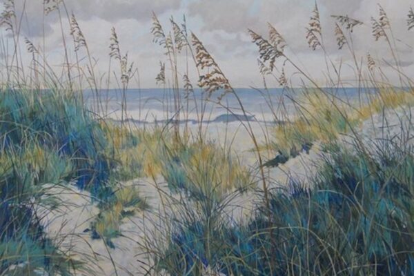 Sand dunes with tall grasses overlook a calm ocean under a cloudy sky. The pathways through the dunes lead toward the shoreline, with gentle waves visible in the background.