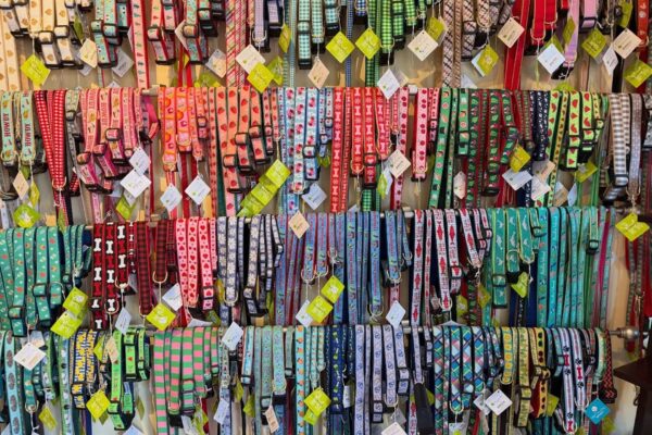 A display wall filled with colorful, patterned dog collars and leashes in various designs, including stripes, paw prints, and geometric shapes, all arranged neatly in rows.