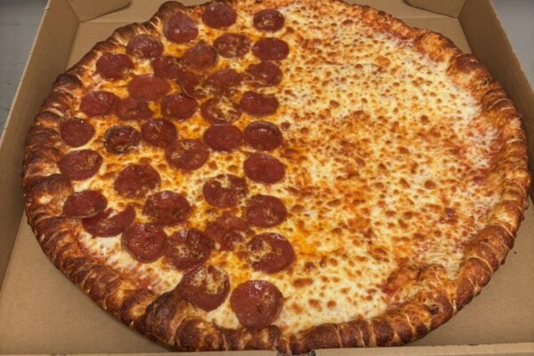 A pizza in an open box, half covered with pepperoni slices and the other half plain cheese, showing a golden-brown crust.